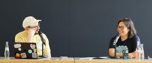 Luke Murphy and Michelle Chin sitting at a desk speaking with each other.