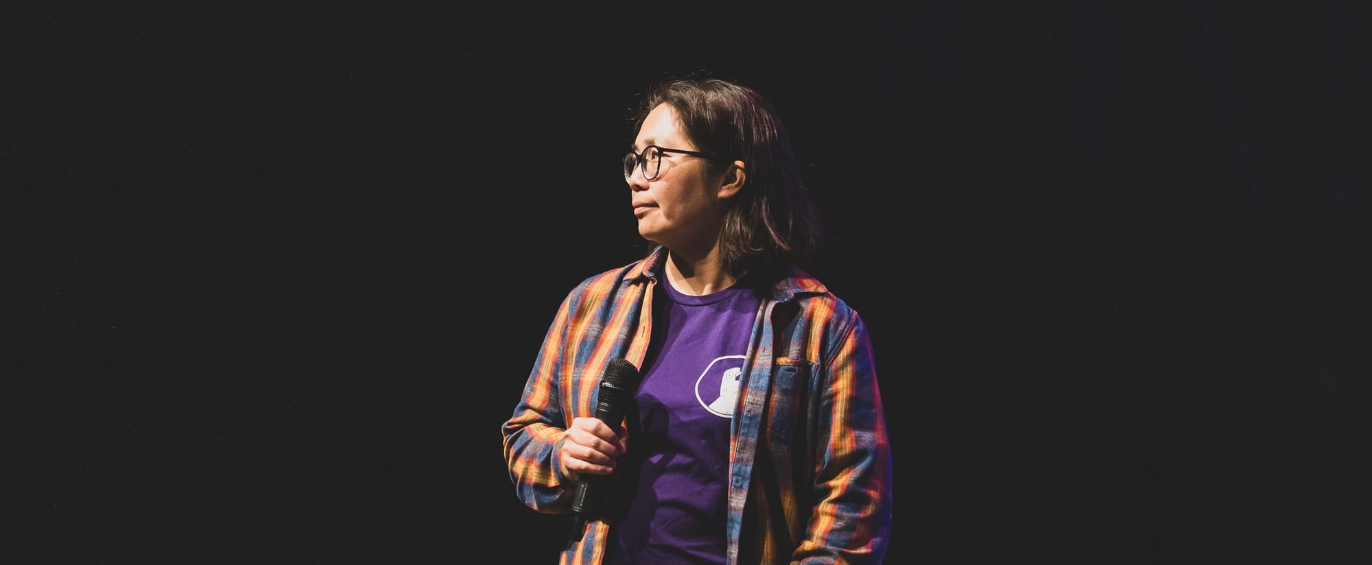 Michelle Chin standing on stage holding a microphone at a conference.